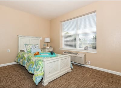 Brightly decorated resident bedroom with window and air conditioning unit
