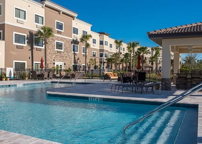 Outdoor pool area with seating and palm trees