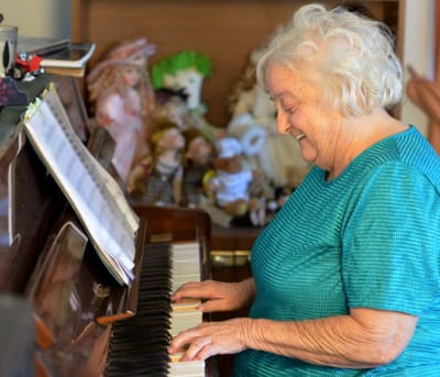 Resident playing piano in a cozy common area