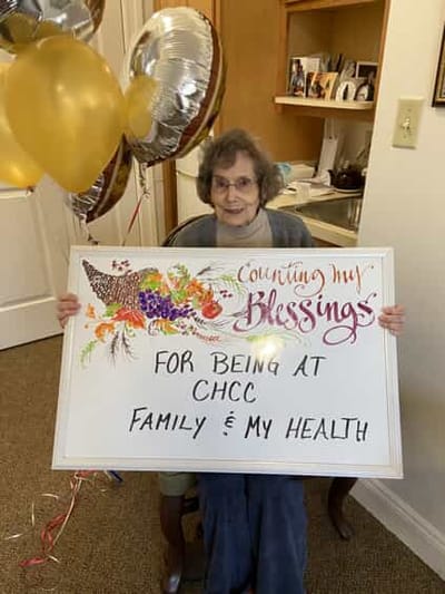 Resident holding a sign of gratitude with balloons