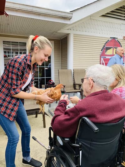 Staff member interacting with a resident holding a chicken