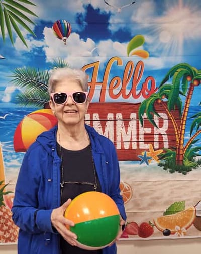 Resident enjoying a summer-themed activity in front of a colorful backdrop