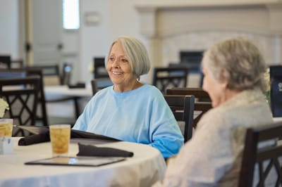 Two smiling senior residents in a dining area