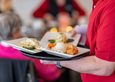 Staff serving meals to residents in a dining area
