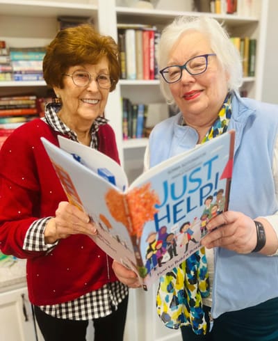 Two residents reading a book in a library setting
