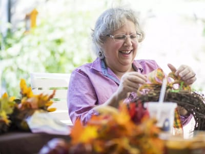 Woman crafting with autumn decorations outdoors
