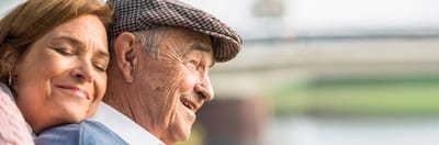 A smiling elderly man and woman enjoying time together outdoors.