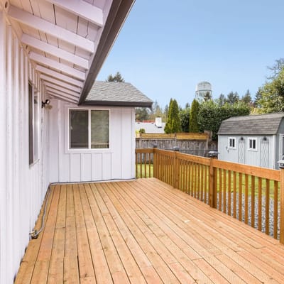 Deck view of a wooden patio with a white house
