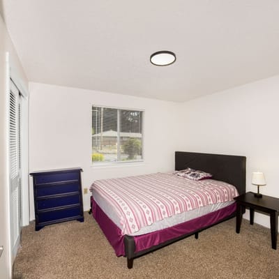 A well-furnished private resident room with a bed and dresser