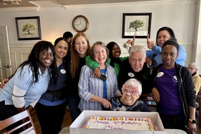 Residents and staff celebrating with a cake in a common area