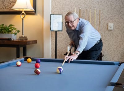 Senior resident playing billiards in a common area