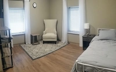 A well-furnished private resident room with a cozy chair