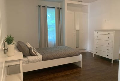 A simple interior of a resident's bedroom with a bed and dresser