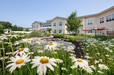 Exterior view of a senior living facility surrounded by flowers