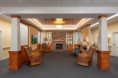 Bright interior lounge area with wooden chairs and a fireplace