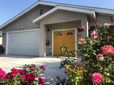 Exterior view of a house with a yellow door and rose bushes
