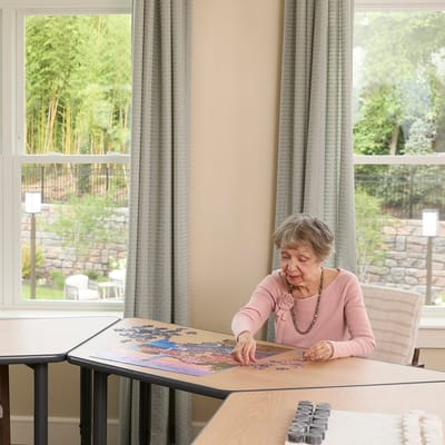 A resident working on a puzzle at a table indoors