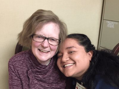 A resident and staff member posing together in a common space