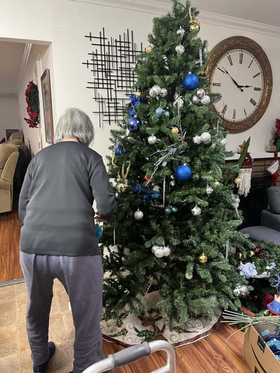 A resident decorating a Christmas tree