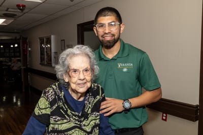 A staff member smiling with a resident in a hall
