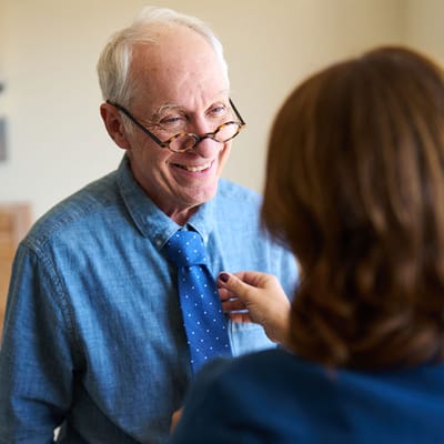 A resident receiving help with a tie in a common area