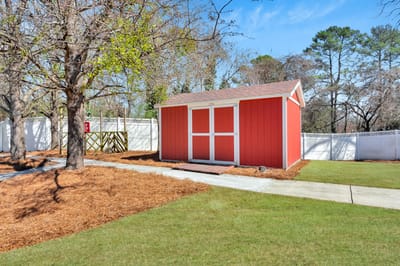 Red storage shed in a landscaped area