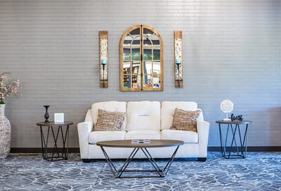 A cozy lounge area with a couch and decorative mirror
