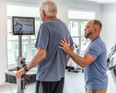 A resident using fitness equipment with staff assistance