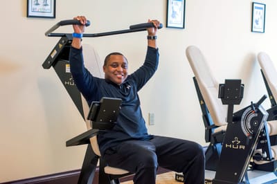A staff member demonstrating exercise equipment in a fitness area
