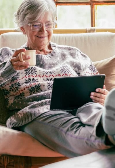 A senior woman enjoying coffee while using a tablet