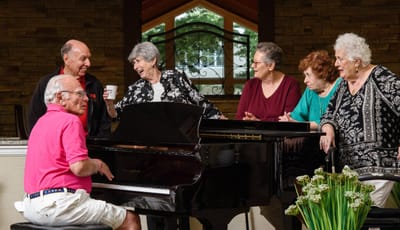 Monroe Village Assisted Living, nursing home in Monroe Township, NJ — Residents enjoying music around a piano in a communal area