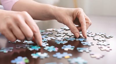 Monroe Village Assisted Living, nursing home in Monroe Township, NJ — Hands assembling a colorful jigsaw puzzle on a table