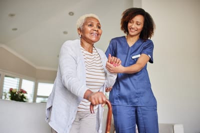 Monroe Village Assisted Living, nursing home in Monroe Township, NJ — Senior resident assisted by staff member with a cane