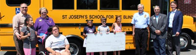 A group photo with children and adults outside a school bus