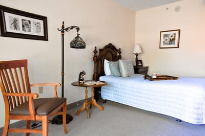 Cozy resident room with bed, chair, and decor.