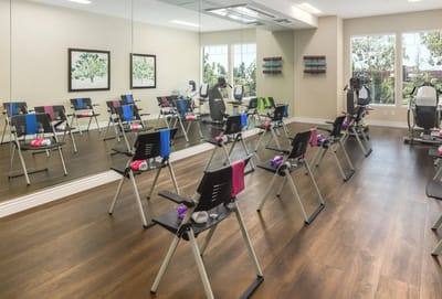 A fitness room with exercise equipment and chairs