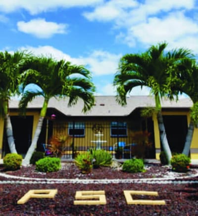 Exterior view of a senior care home surrounded by palm trees