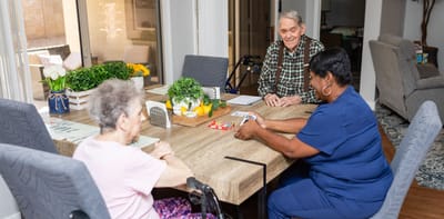 Residents engaging in a card game at a dining table