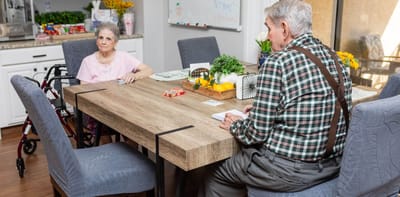 Two residents engaged in a game at a dining table