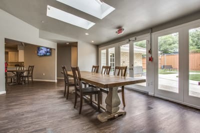 Well-lit dining area with large table and outdoor view