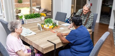 Residents and staff engaged in a card game at a table