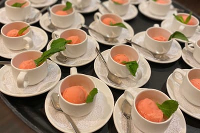 Plates of dessert served in cups with mint leaves