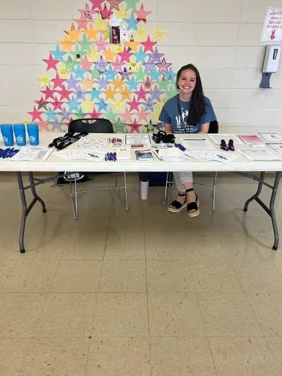 Staff member at a table with promotional materials.