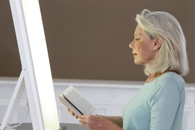 A senior woman reading a book in a well-lit space.
