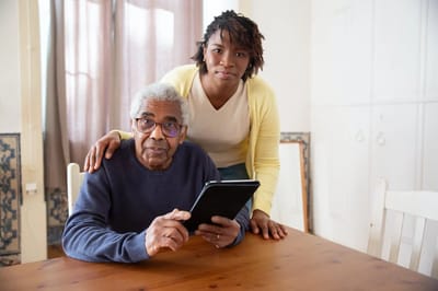 Elderly man using a tablet with caregiver