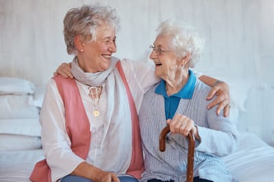 Two elderly women laughing and embracing.
