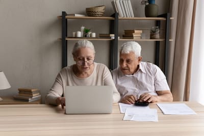 Elderly couple using a laptop at a table.