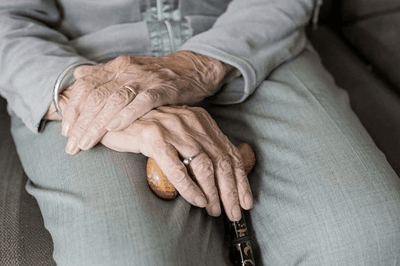 Close-up of hands resting on a cane