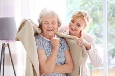 Happy resident receiving a blanket from staff.
