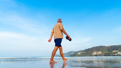 An elderly man walking on the beach.